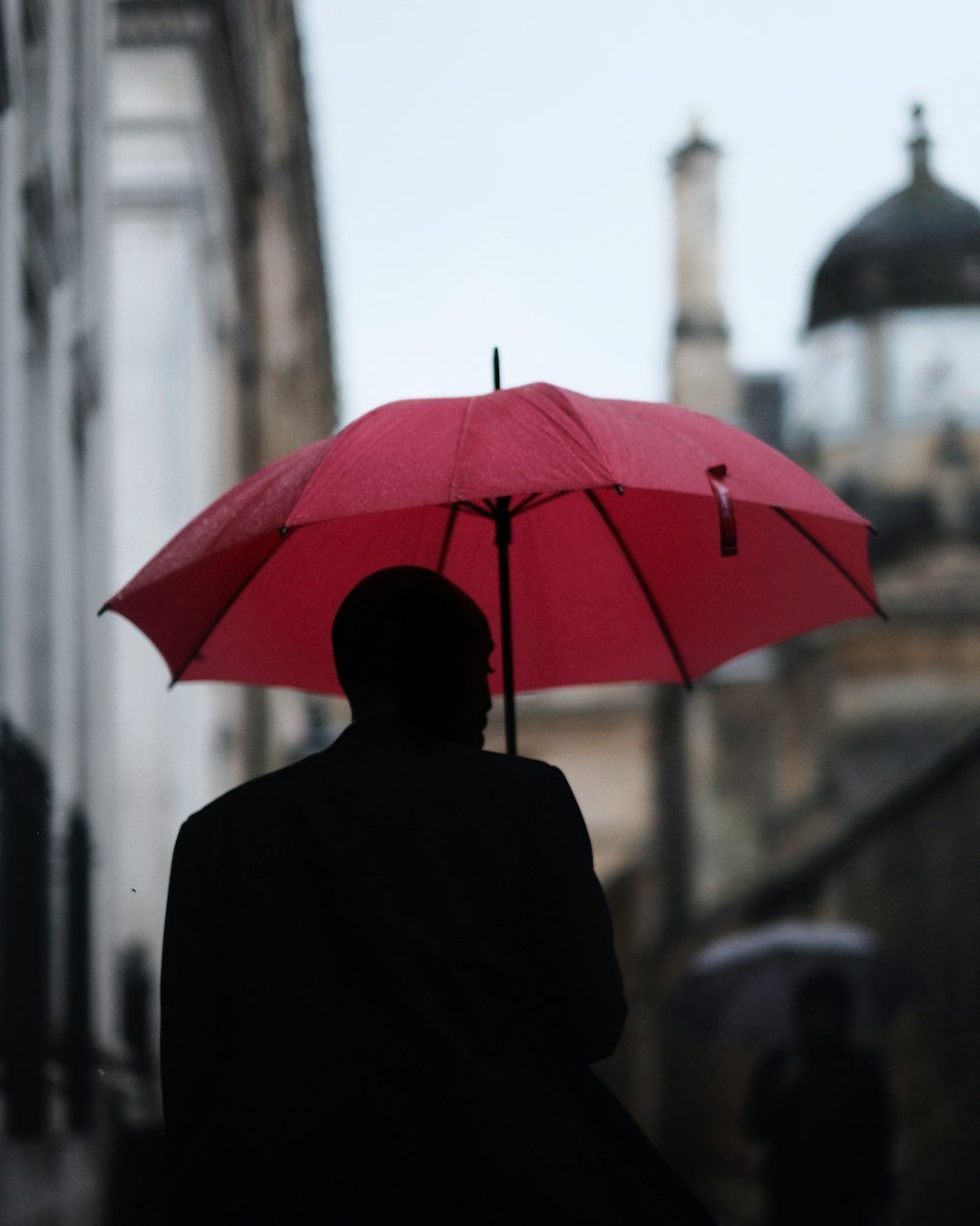 Accueil a man with a red umbrella disappears down senate house passage in cambridge uk
